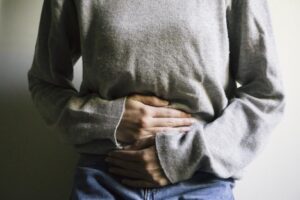 Woman losing weight due to digestive disorders is holding her stomach