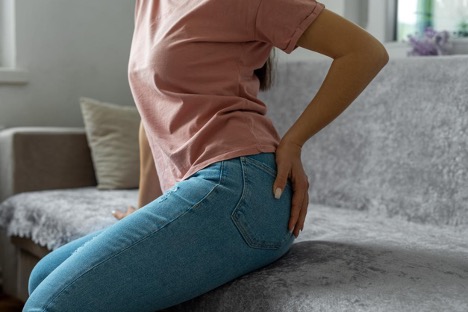 A woman holding her buttocks due to hemorrhoid pain.